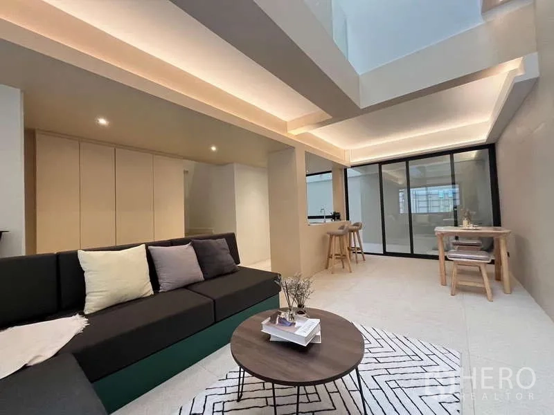 Townhouse for sale in Khlong Toei, Bangkok - Open-plan living and dining area with cove lighting and breakfast bar kitchen.