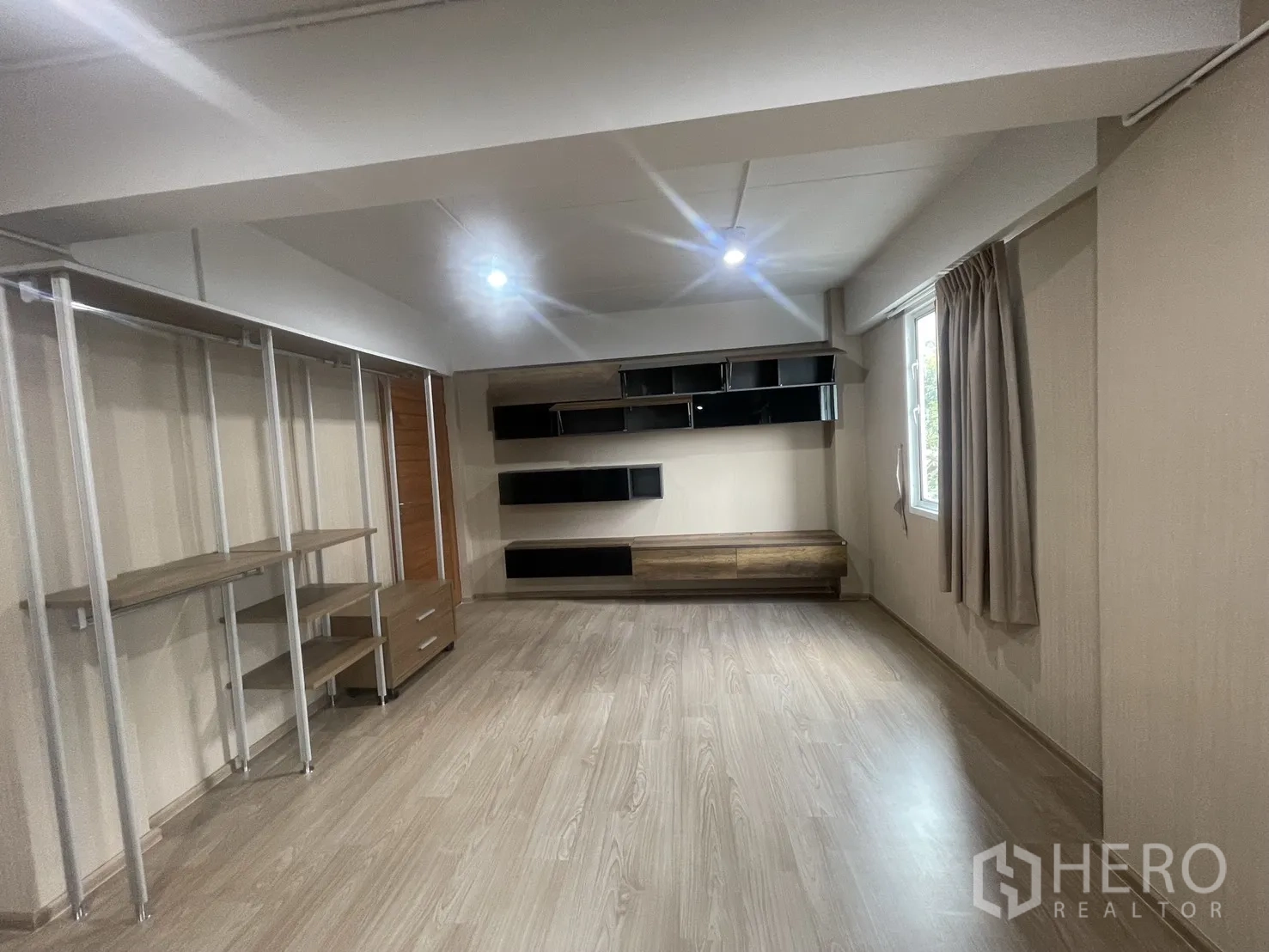 Home Office for rent in Suan Luang, Bangkok - Spacious office or bedroom with built-in shelving, window, and light wood floors.