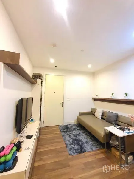 Condominium for sale in Bangkok - Bright lounge with recessed lighting, media console, and sofa facing the entry door.