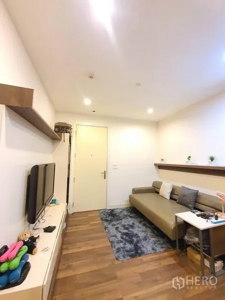 Condominium for sale in Bangkok - Bright lounge with recessed lighting, media console, and sofa facing the entry door.