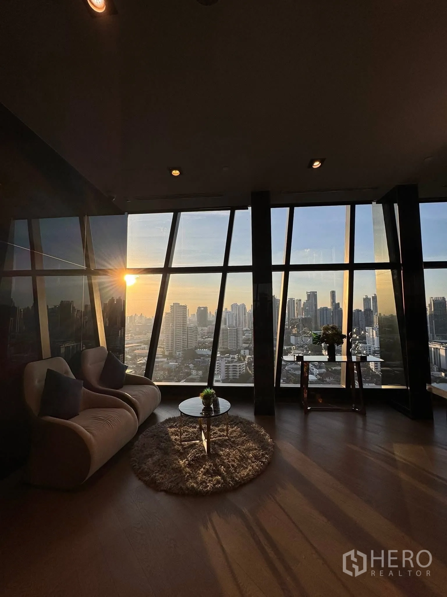 คอนโด for rent in Khlong Toei, Bangkok - มุมนั่งเล่นอบอุ่น โซฟาและโต๊ะกาแฟ มองเห็นวิวพระอาทิตย์ตก