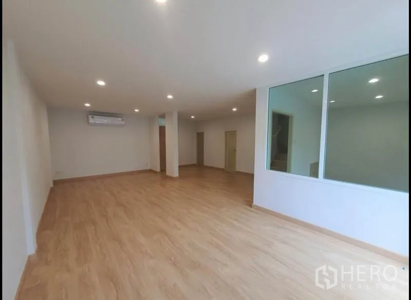 Townhouse for rent in Phaya Thai, Bangkok - Spacious living and dining area with split air conditioner, wood flooring and large interior glass panels.