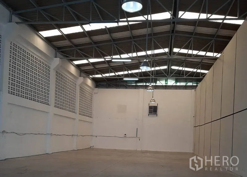 Warehouse for rent in Suan Luang, Bangkok - High-ceiling warehouse interior with steel truss roof, skylights and concrete floor.