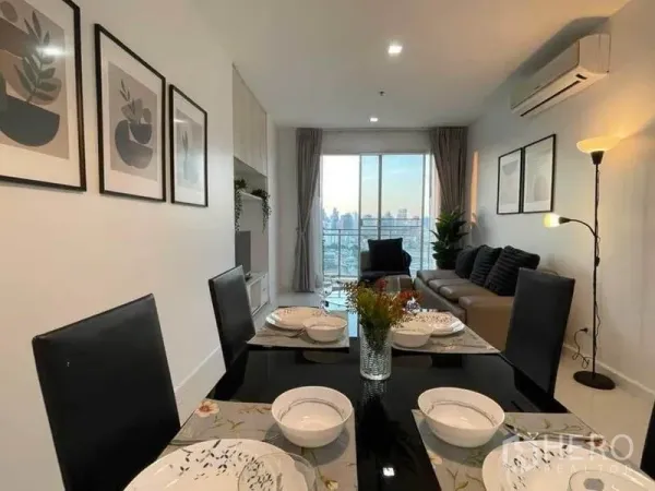 Condominium for rent or sale in Watthana, Bangkok - Dining table setting with view toward living area and city skyline beyond the balcony.