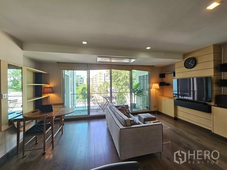 公寓 出售在Phra Khanong, Bangkok - 采光充足的客厅，沙发与电视墙，落地推门通向阳台眺望绿景。