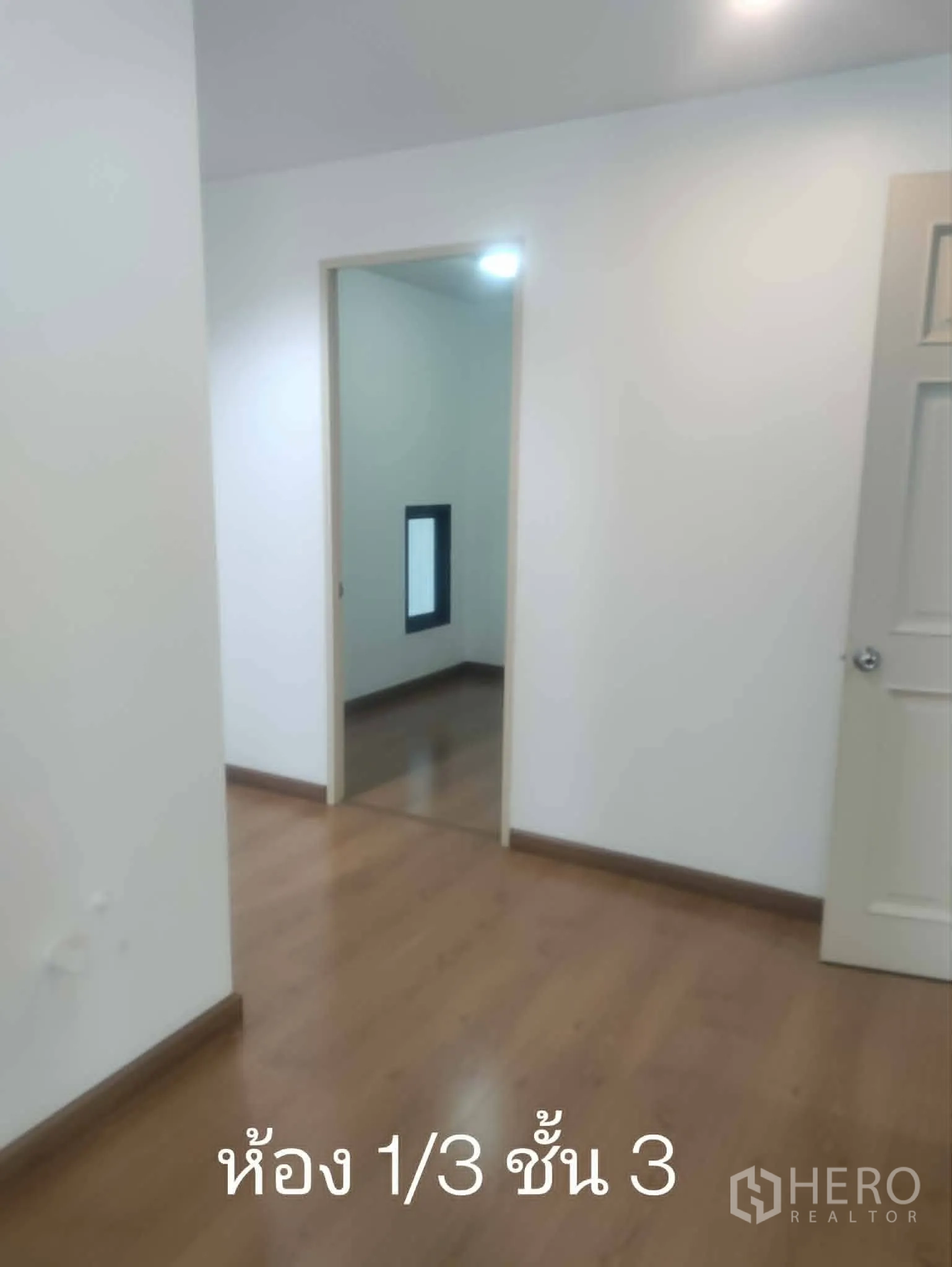 Home Office for rent in Lat Phrao, Bangkok - Small room off the corridor with wood floors and white walls.