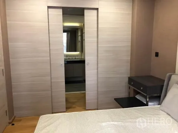 Condominium for rent in Pathum Wan, Bangkok - Bedroom view to sliding pocket doors leading to the bathroom vanity area.