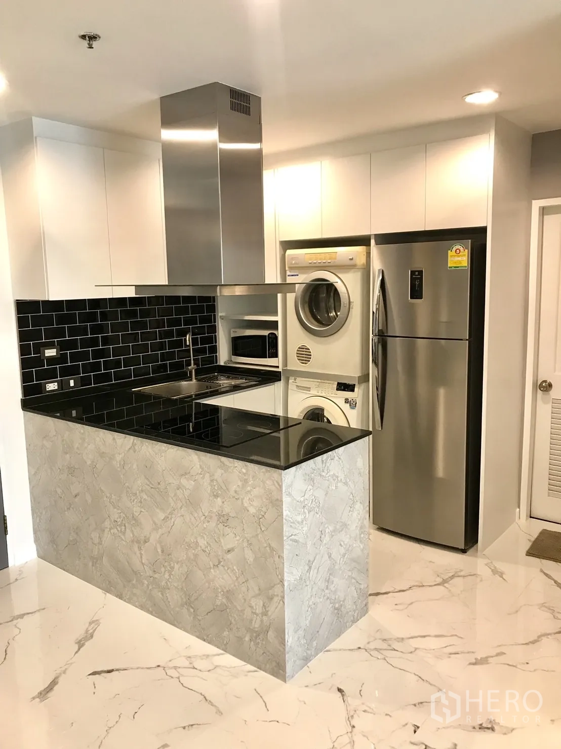 公寓 出租或出售在Khlong Toei, Bangkok - 紧凑厨房，黑色砖背墙，电磁炉、双门冰箱与洗烘一体机。