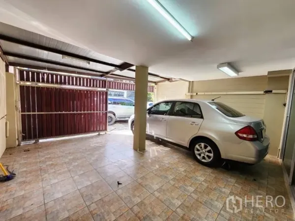 Home Office for rent in Khlong Toei, Bangkok - Covered carport with tiled floor, fluorescent lighting, and sliding metal gate, offering space for one to two cars.