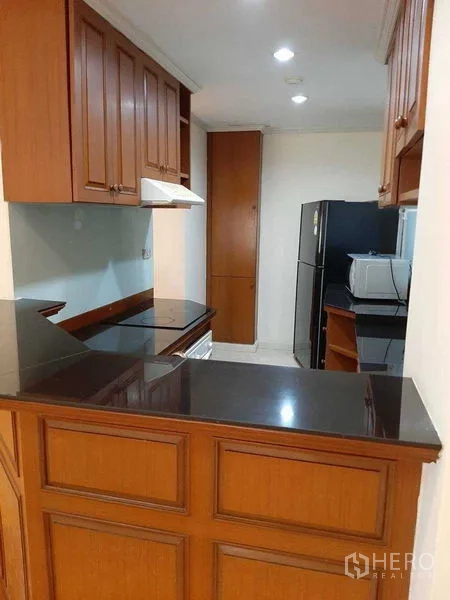 อพาร์ทเมนท์ ให้เช่าในWatthana, Bangkok - ครัวยูเชป ตู้ไม้ เคาน์เตอร์หินสีดำ เตาและฮูด ตู้เย็น และไมโครเวฟ