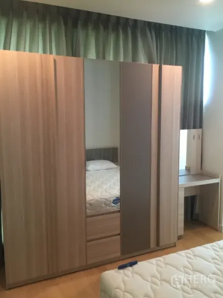 Condominium for rent in Bang Kho Laem, Bangkok - Built-in wooden wardrobe with mirror and a dressing table beside the window.