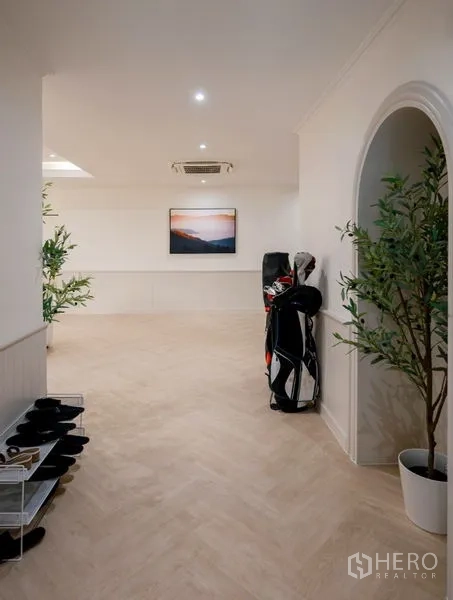 Condominium for sale - Hallway with arched niche, indoor plants, and golf bags.