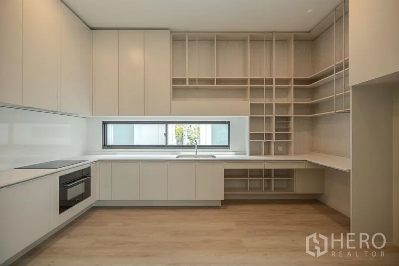 Detached House for rent in Saphan Sung, Bangkok - Minimalist white kitchen with ample cabinetry, open shelving and window.