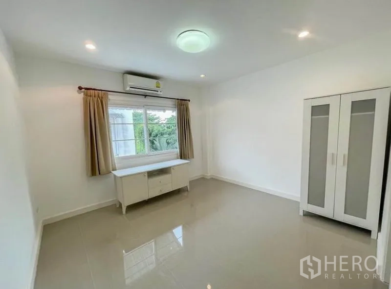 Townhouse for rent in Phasi Charoen, Bangkok - Simple bedroom with window, wardrobe and desk facing garden views.
