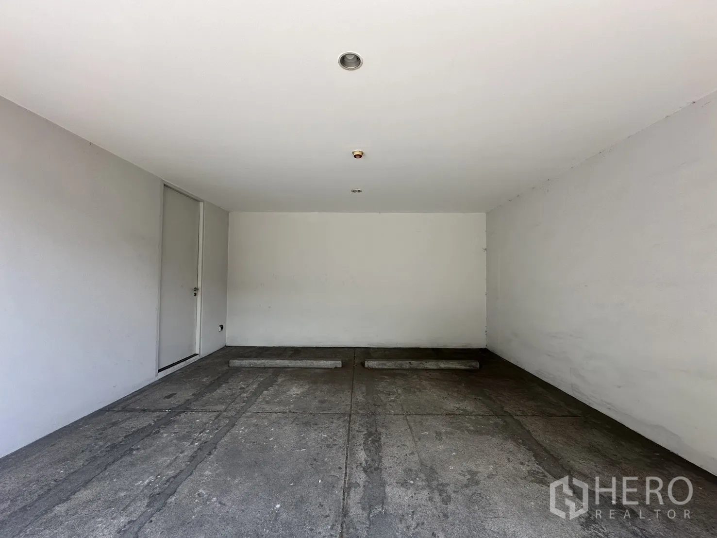 Home Office for rent in Phra Khanong, Bangkok - Covered carport with two parking bays, white walls, and a side door.