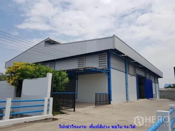 โรงงาน ให้เช่าในSamut Sakhon - ภาพภายนอกโรงงานโครงสร้างเหล็ก ประตูม้วน โทนสีน้ำเงิน พร้อมหลังคาโหลดสินค้า ที่สมุทรสาคร