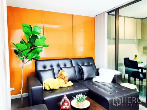 สำนักงานที่บ้าน ให้เช่าในKhlong Toei, Bangkok - โซนนั่งเล่นอบอุ่น โซฟาหนังสีดำ ผนังลายไม้ และต้นไม้ตกแต่ง