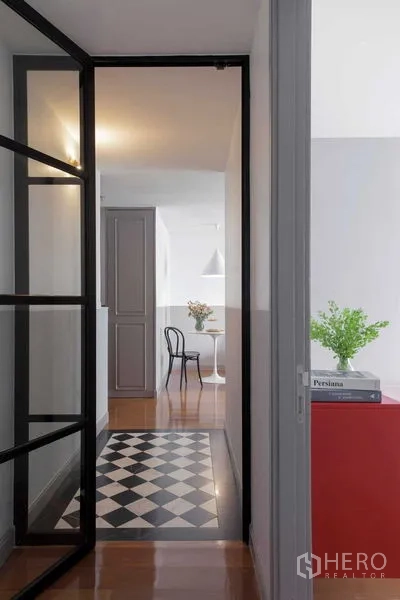 Condominium for sale in Watthana, Bangkok - Hallway with black-framed glass door and checkerboard floor tiles facing the dining nook.