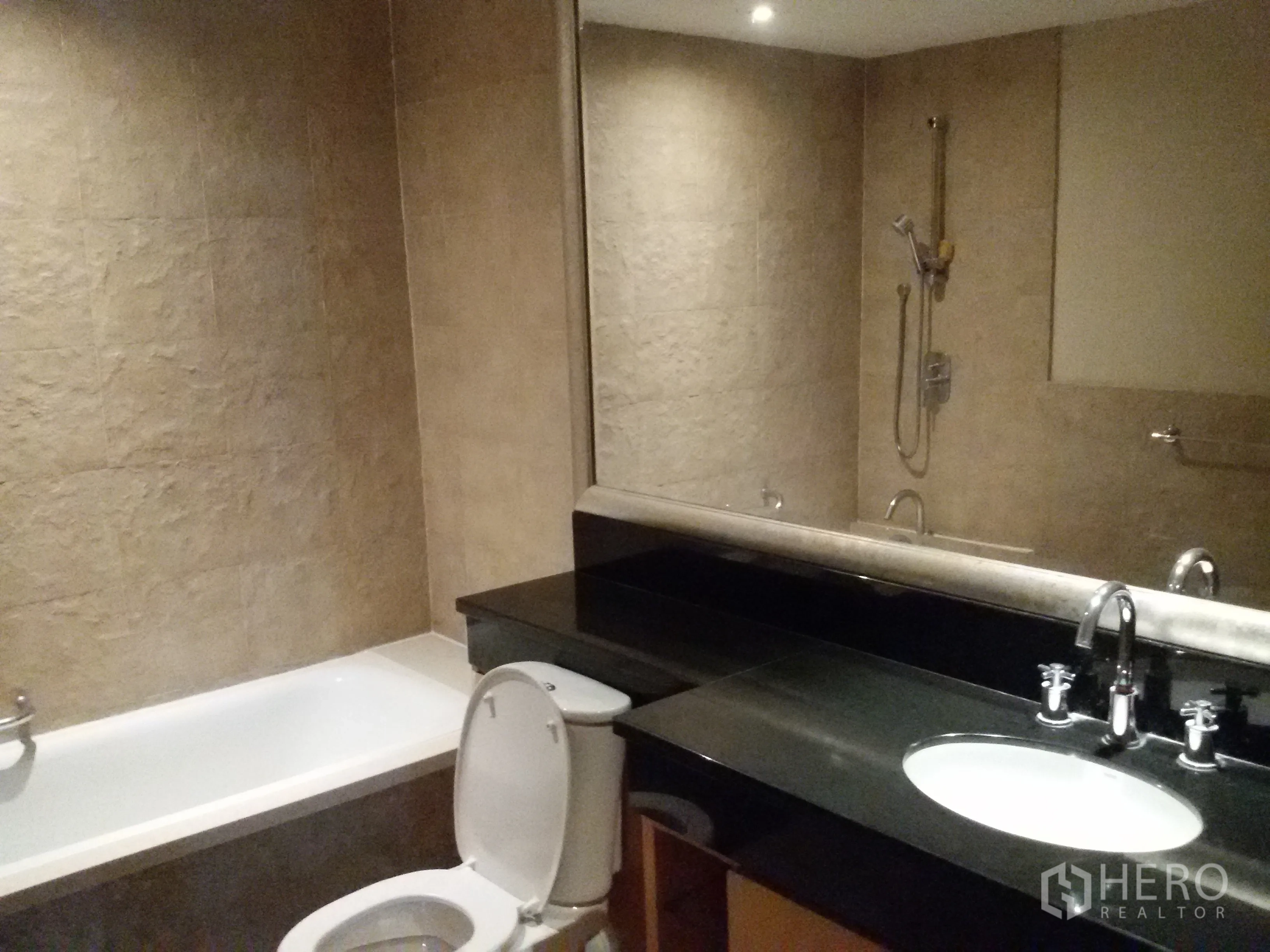 Condominium for rent in Sathon, Bangkok - Contemporary bathroom featuring a bathtub, large mirror and black stone vanity.