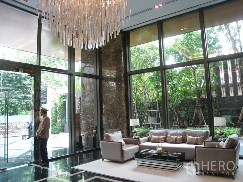 Condominium for rent in Watthana, Bangkok - Elegant lobby seating area under a statement chandelier with garden views through tall windows.