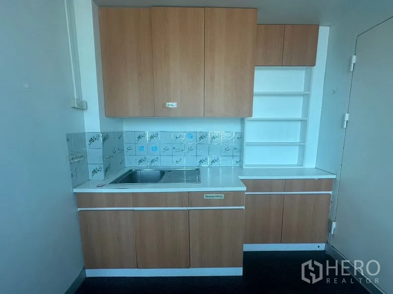 Office Space for rent in Khlong Toei, Bangkok - Compact staff pantry with sink, wood cabinets, shelves and a tiled backsplash.