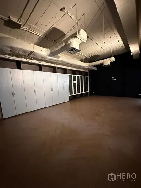 Office Space for rent in Watthana, Bangkok - Private office room featuring wood flooring, long white storage cabinets, and a dark accent wall.