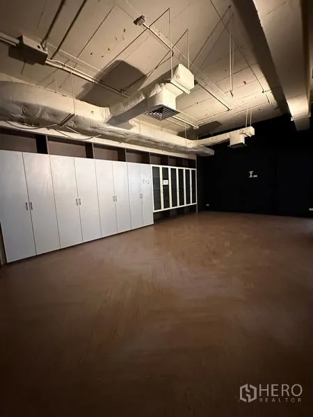 Office Space for rent in Watthana, Bangkok - Private office room featuring wood flooring, long white storage cabinets, and a dark accent wall.