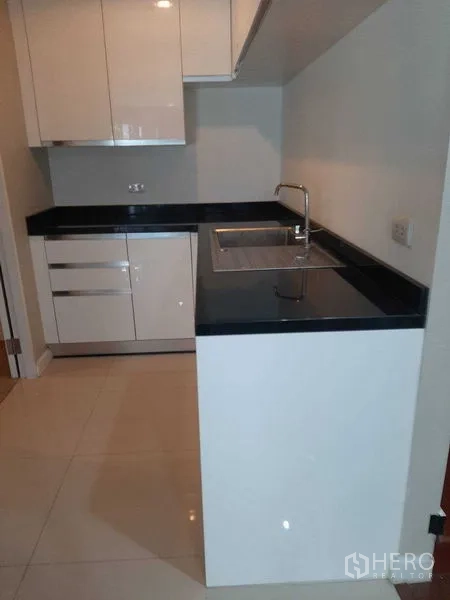 Condominium for rent or sale in Huai Khwang, Bangkok - Compact modern kitchen with white cabinetry, black countertops and a stainless sink