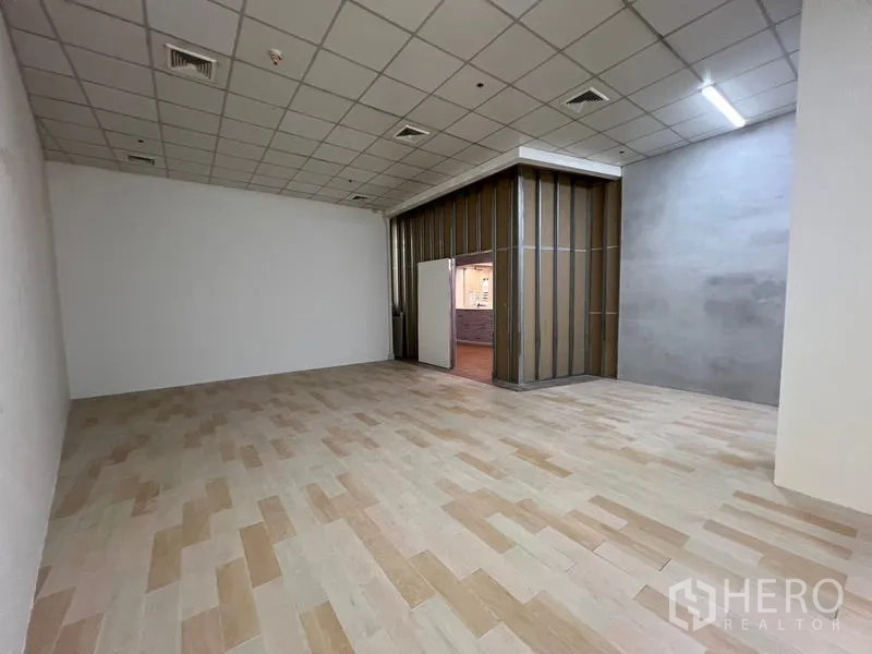 零售空间 出租在Watthana, Bangkok - 商铺一角，带隔断与出入口，浅色墙面和木纹地砖。