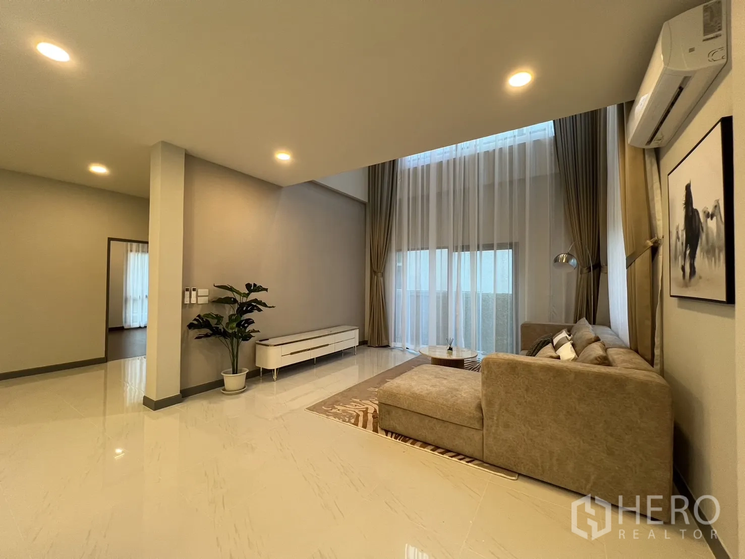 Detached House for rent or sale in Bang Phli, Samut Prakan - Living area with column, L-shaped sofa, sheer drapes and indoor plant.