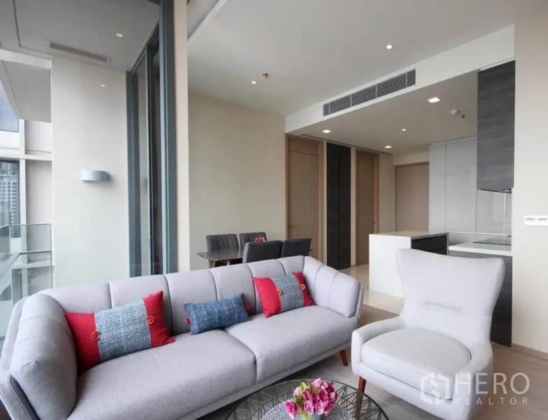 Condominium for rent in Watthana, Bangkok - Living area with plush sofa and armchair opening to a balcony with skyline views.