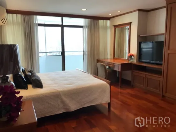 Condominium for rent in Watthana, Bangkok - Master bedroom with large bed, built-in desk and TV unit, floor-to-ceiling curtains and balcony access.