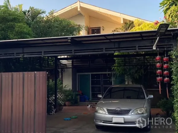 Detached House for sale in Wang Thonglang, Bangkok - Front facade with covered parking area and greenery surrounding the detached house.