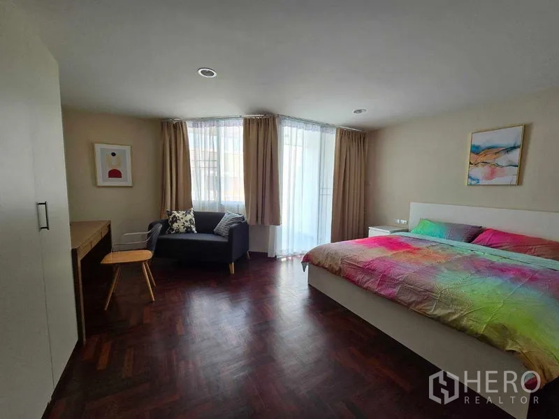 ทาวน์เฮาส์ ให้เช่าในBang Na, Bangkok - ห้องนอนหลักกว้าง โปร่งสว่าง มีโซฟา โต๊ะทำงาน และพื้นลายไม้