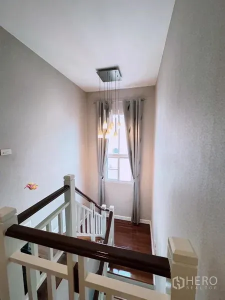 Detached House for rent in Prawet, Bangkok - Staircase with wooden handrail, pendant lights, and a curtained window.