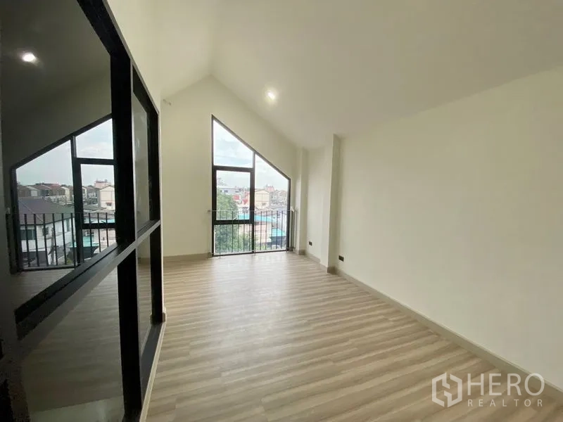 Home Office for rent or sale in Bang Na, Bangkok - Spacious living or office area with sloped ceiling and two tall balcony doors bringing in natural light.