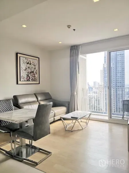 公寓 出租在Watthana, Bangkok - 采光充足的客厅，真皮沙发、石材茶几并连接可观赏天际线的阳台。