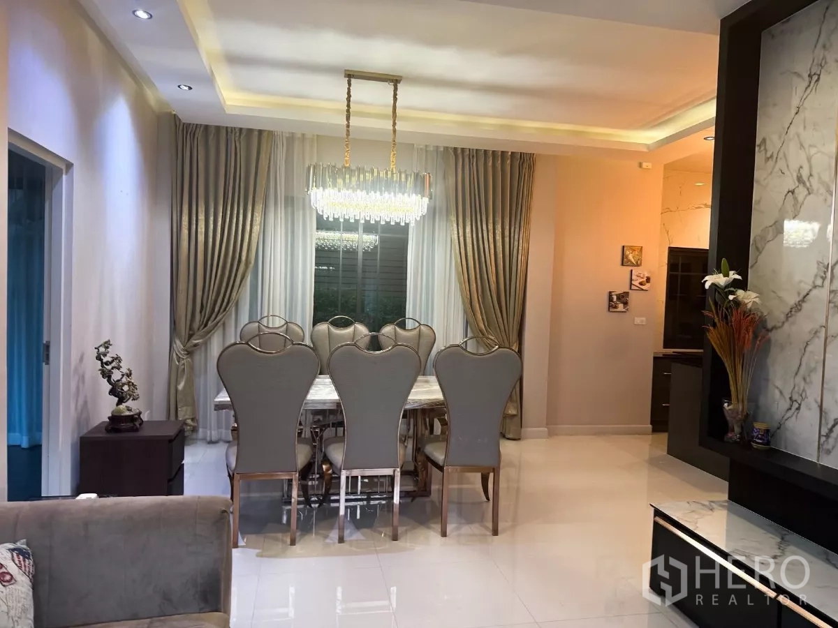 Detached House for rent or sale in Bang Phli, Samut Prakan - Formal dining space with a crystal chandelier, full‑length drapes and a marble TV wall.