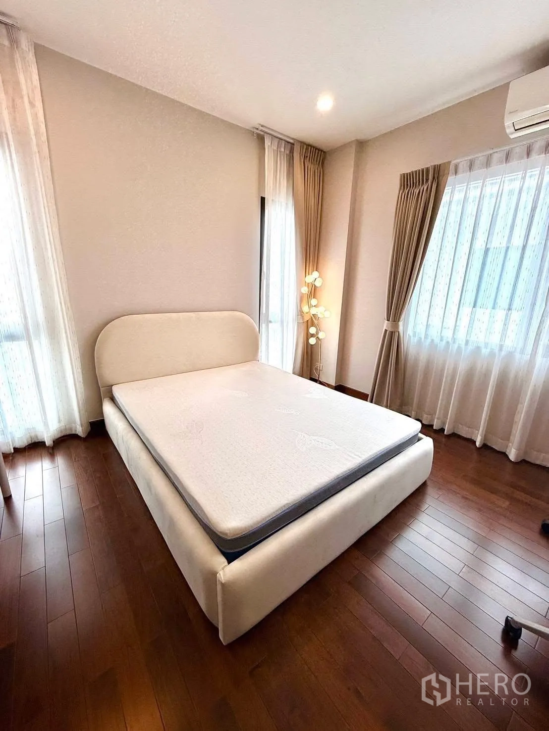 Detached House for rent or sale in Wang Thonglang, Bangkok - Corner bedroom with large windows and upholstered bedframe.