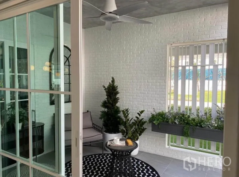 Detached House for rent in Bang Phli, Samut Prakan - Enclosed patio or sunroom with white brick walls, ceiling fan and potted greenery.