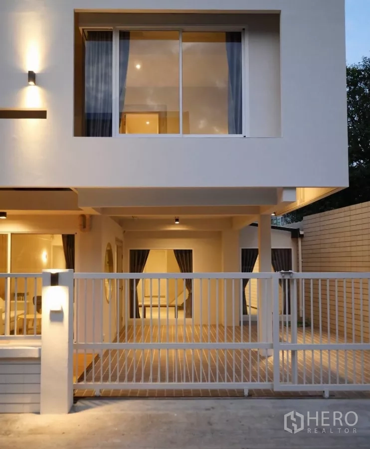 联排别墅 出租或出售在Watthana, Bangkok - 正立面近景，上层大滑窗与金属栅栏车道入口。