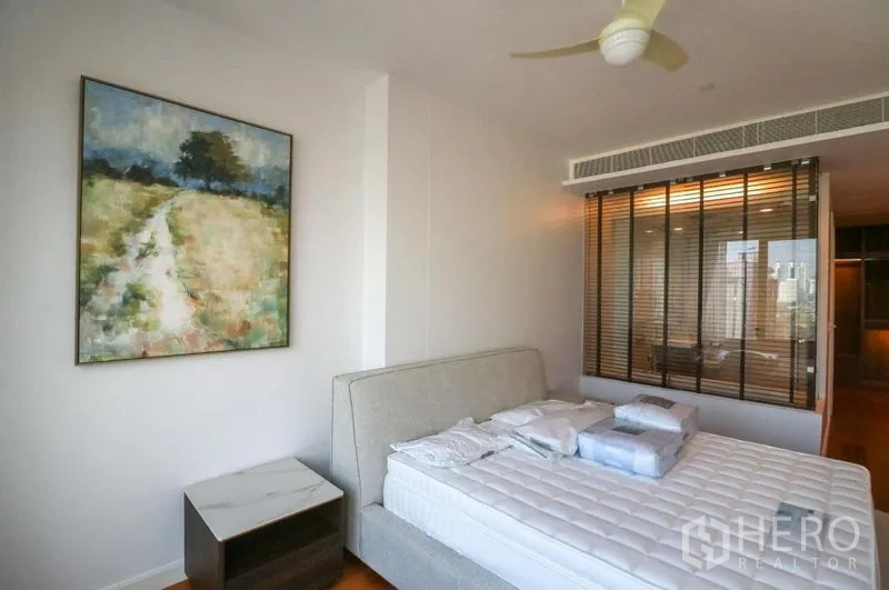 Condominium for rent in Pathum Wan, Bangkok - Primary bedroom with large bed, artwork and a glass wall to the bathroom.