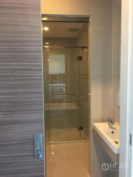 公寓 出租在Watthana, Bangkok - 当代风格卫浴，米色瓷砖，玻璃干湿分离淋浴间与小型洗手台。