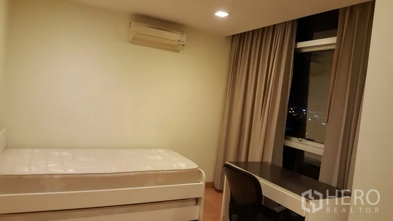 คอนโด ให้เช่าในKhlong Toei, Bangkok - ห้องนอนรอง เตียงเดี่ยว โต๊ะทำงาน ข้างหน้าต่างวิวเมืองยามค่ำ พร้อมแอร์