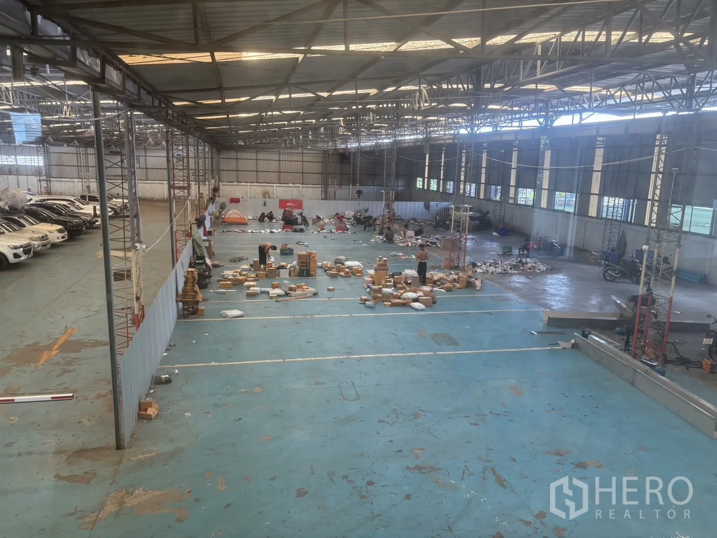 โรงงาน for rent or sale in Bang Sao Thong, Samut Prakan - พื้นที่โกดังขนาดใหญ่ หลังคาโครงเหล็ก แผงสกายไลท์ พื้นสีน้ำเงิน มีที่จอดรถด้านข้าง.