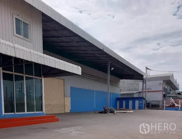 工厂 出租在Lat Lum Kaeo, Pathum Thani - 带雨棚的装卸区，卷帘门连接仓库与开放场地。