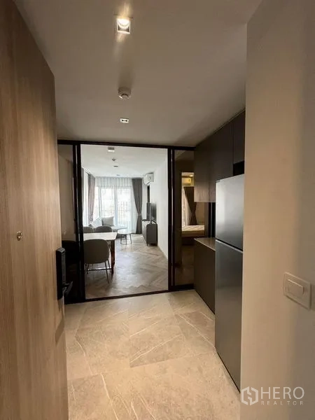 Condominium for rent in Watthana, Bangkok - Entry hallway with kitchenette and glass partition leading to a bright living area in a modern Bangkok condo.