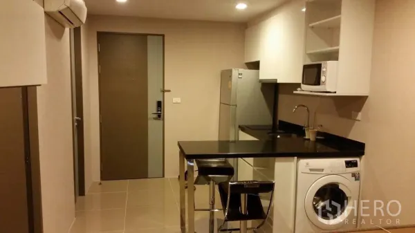 คอนโด ให้เช่าในWatthana, Bangkok - ครัวแบบเปิดเคาน์เตอร์หินสีดำ มีโต๊ะบาร์ ตู้เย็น ไมโครเวฟ และเครื่องซักผ้าฝาหน้า