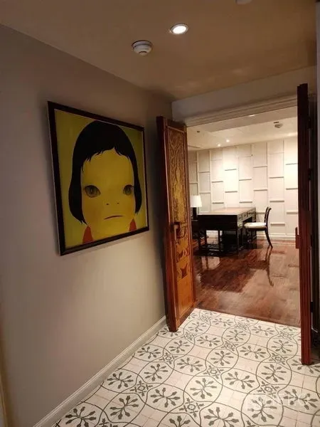 Condominium for rent in Bang Rak, Bangkok - Corridor displaying contemporary portrait art leading to a study with paneled walls and wooden floors.