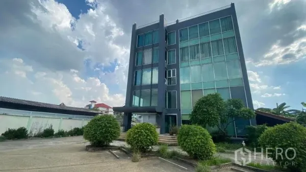 Office Space for sale in Bang Kapi, Bangkok - Front elevation of the office building showing large windows, landscaped shrubs and a wide forecourt.